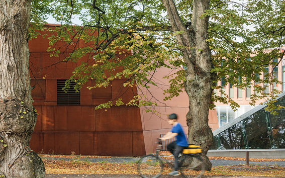 Mies pyöräilemässä Aalto-yliopiston metroaseman edessä